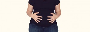 Woman with hands on stomach.